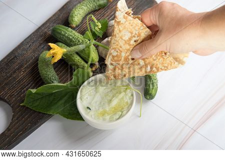A Womans Hand Dips Pita Bread In Tzatziki Sauce Made Of Yogurt And Grated Cucumbers With Garlic. Nat