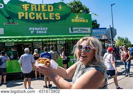 Falcon Heights, Minnesota - August 30, 2021: Happy Laughing Woman Holds Up Her Deep Fried Pickles Fr