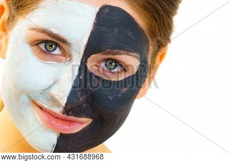 Woman With Clay Carbo Black Mask On Half Face And White Mud On Second Half. Girl Taking Care Of Oily