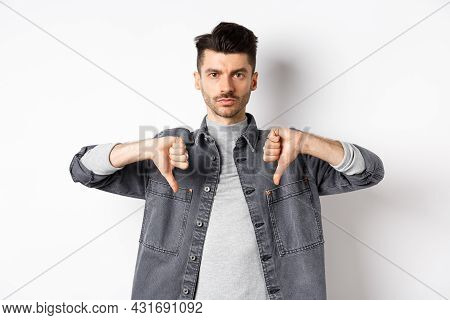 Very Bad. Serious Man Showing Thumbs Down And Look At Camera With Pokerface, Telling No, Disapprove 