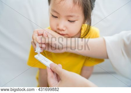 Close Up Shot Of Example Liquid Dropping On Cartridge Of Covid-19 Tester While Toddler Nearby With A