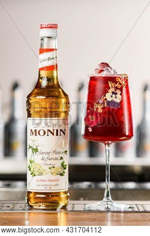 Ukraine, Kyiv - March 12, 2021: Bottle Of Saveur Fleur De Sureau Syrup And Glass Of Cold Red Cocktai