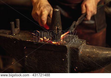 Close-up Hands Of Male Blacksmith Forge An Iron Product In A Blacksmith. Hammer, Red Hot Metal And A