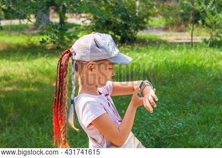 Kid Using Smartwatch Outdoor. Child Talking On The Smartphone. Schoolgirl Using Touchscreen On Watch