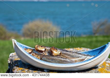 Smoked Sprattus Or Sprats Sea Fish Served Outdoor With View On Blue Sea Water