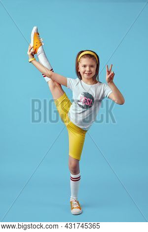 Vertical Photo Of Flexible Little Cute Kid In Yellow Sportswear Perform Transverse Twine While Showi