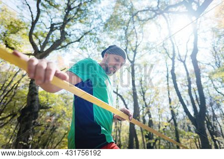 Portrait Of A Man Slackliner Next To A Stretched Slack In The Autumn Forest. Copy Space For Slack Ev