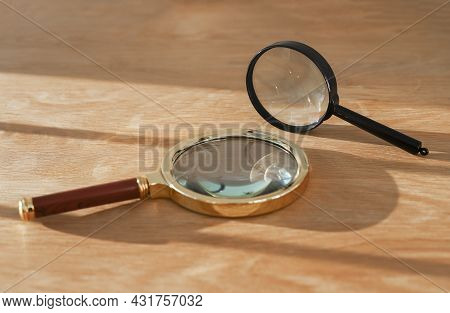 Two Magnifying Glasses On Wood Desk With Daylight. Concept Of Observation, Exploration, Study And Re
