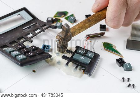 Nervous, Irritated Man Smashes Calculator With Hammer. His Hand Hits The Plastic Casing Of The Elect