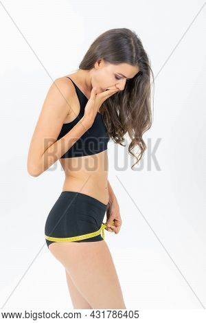 ฺbeautiful Young Woman In Good Shape She Wears Exercise Clothes Using A Tape Measure To Measure Her 