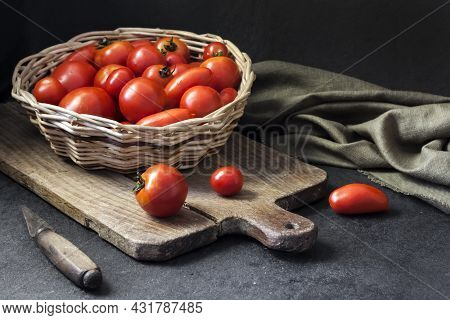 Fresh Red Tomatoes In Whicker Basket On Black Background.
