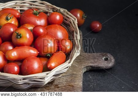 Fresh Red Tomatoes In Whicker Basket On Black Background.