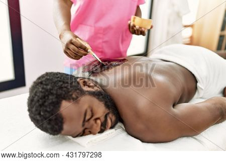 African american man reciving skin treatment on his back at beauty center.