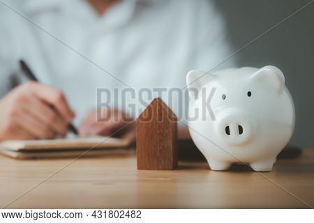 Piggy Bank With Man Doing Finances And Calculate On Desk About Cost At Home Office.
Concept Of Save,
