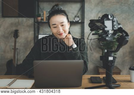 Smiling Asian Girl Sitting In Front Of Camera On Stabilizer, Recording Self-presentation Video Or Sh