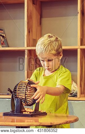 Blond Curious Child Boy Facial Expression Gesture Play Lotto Round Sphere Spins With Small Orange Ba