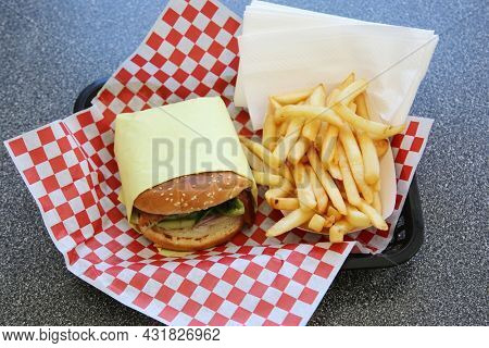 Cheeseburger with french fries. Lunch of Fresh Grilled Cheese Burger and French Fries on a red and white checker place mat in a fast food restaurant. Everyone enjoys Cheese Burgers and Fries for Lunch