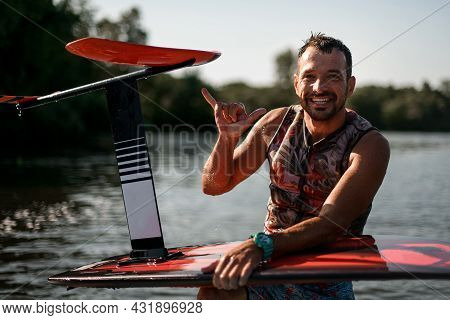 Cheerful Smiling Wet Men Holds Foil Board And Shows A Gesture With His Hand
