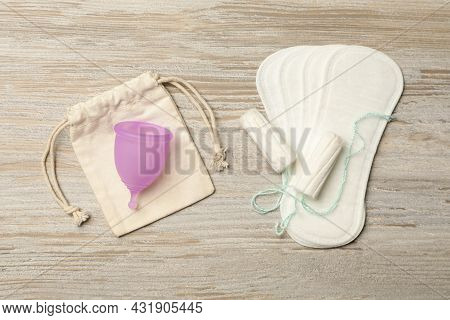 Menstrual Cup With Bag, Pantyliners And Tampons On Wooden Background, Flat Lay
