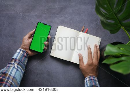 Top View Of Man Hand Using Smart Phone And Reading A Book