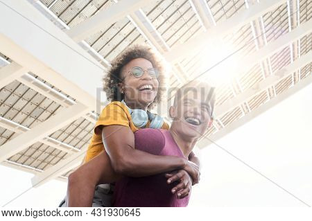 Young Smiling Lovers Looking At The Camera. The Girl Is Piggyback On Her Boyfriend. Concept Of Frien
