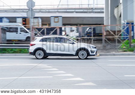 White Kia Rio X-line Driving On A City Road. Side View Of Compact Hatchback Kia Kx Cross Speeding In