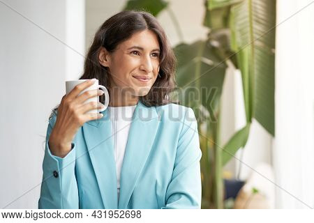 Young Smiling Latina Business Woman, Satisfied With A Job Well Done, Relaxing With Her Morning Coffe