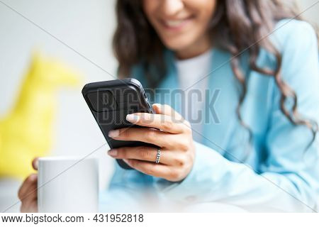 Close Up Of Hands Of Unrecognizable Business Woman Drinks Coffee Sitting On A Sofa While Using A Sma