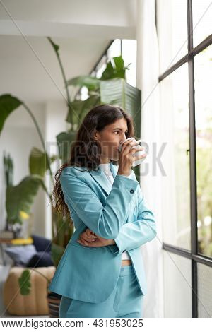 Vertical Photo Of A Young Businesswoman Enjoying Her Morning Coffee Or Tea, Looking Out The Window. 