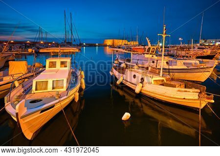 Venetian Fort Venetian fortress of Koules Castello a Mare castle in Heraklion and moored Greek fishing boats in port, Crete Island, Greece in twilight