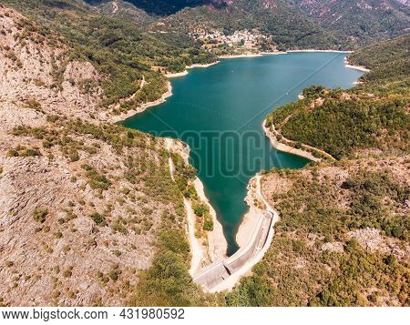 Aerial View Of The Dam Wall At Lac De Tolla And The Village Of Tolla In Corsica Surrounded By Pine F