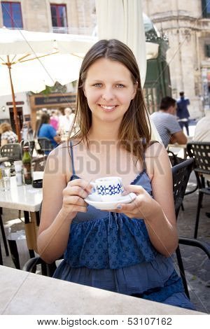 Woman Drinking Coffee In Outdoor Cafe