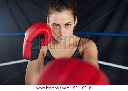 Portrait of a beautiful young woman in red boxing gloves in the ring