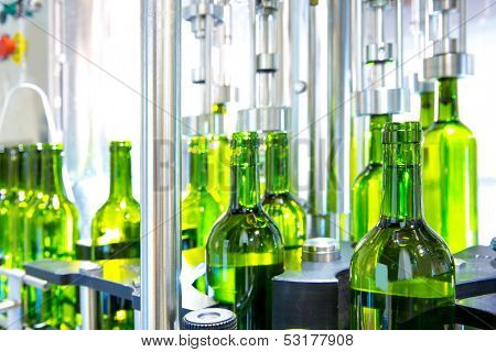 white wine in glass bottling machine at winery