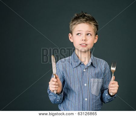 Little boy with fork and knife. Hungry child.