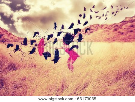  a girl in a field with an umbrella pointing toward a flock of birds done with a warm filter