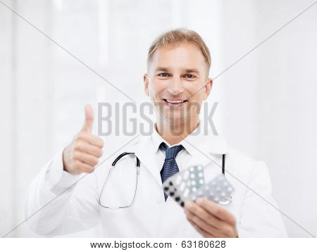 healthcare, medical and pharmacy concept - male doctor with packs of pills