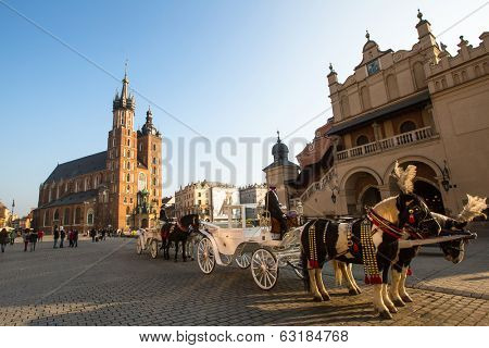 KRAKOW, POLAND - FEB 26, 2014: Carriages at Main Market Square. It dates to the 13th century, and at roughly 40,000 m it is the largest medieval town square in Europe.