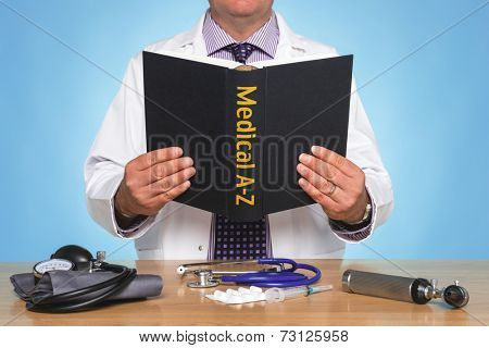 Doctor sat at a desk reading a Medical A-Z book