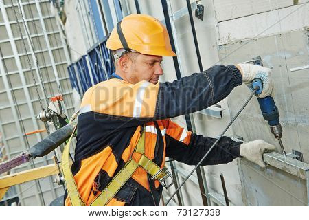 worker builder making construction for ventilation facade on a building with screwdriver drill
