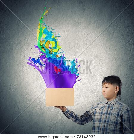 Young boy splashing colorful paint from carton box