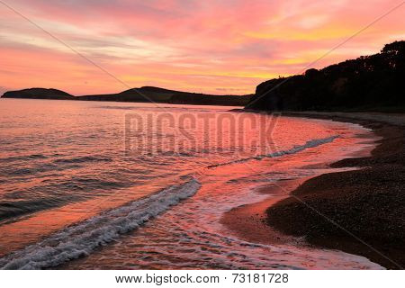 waves on the beach against red sunset of russian isle Putyatin 