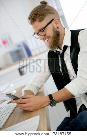 Treny guy in office sending text message with smartphone