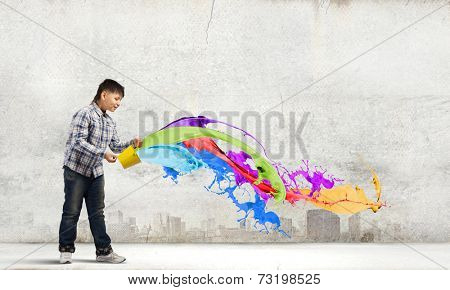 Young boy splashing colorful paint from bucket