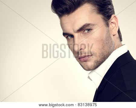 Fashion young businessman black suit casual  poses at studio