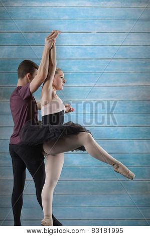 Ballet partners dancing against wooden planks
