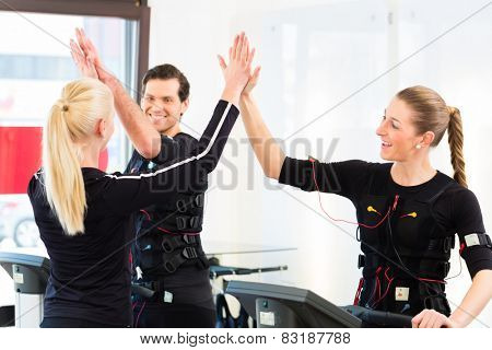 Female coach giving man and woman nms electro muscular stimulation exercise 