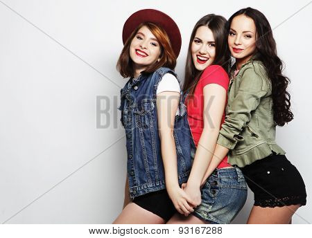 Three stylish sexy hipster girls best friends.Standing together and having fun. Looking at camera. Over gray background.