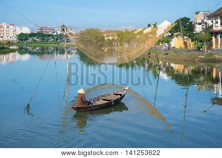 HOI AN, VIETNAM - JANUARY 04, 2016: The fisherman on the boat with fishing net on the Thu Bon river in the early morning. Tourist landmark of the city Hoi An, Vietnam