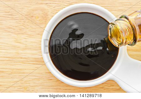Oyster sauce in white bowl on wooden background.